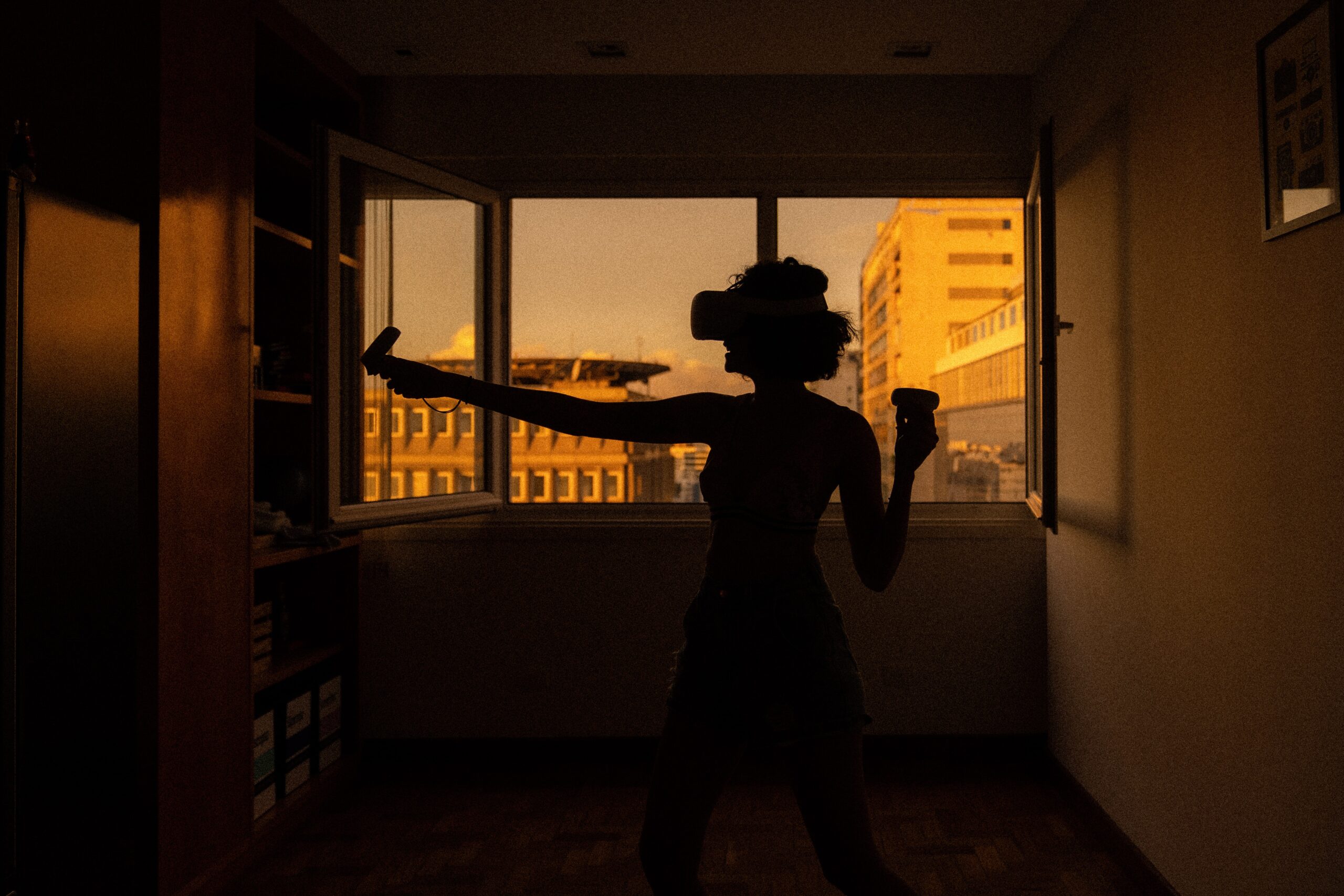 Silhouette of woman standing near window sill using VR